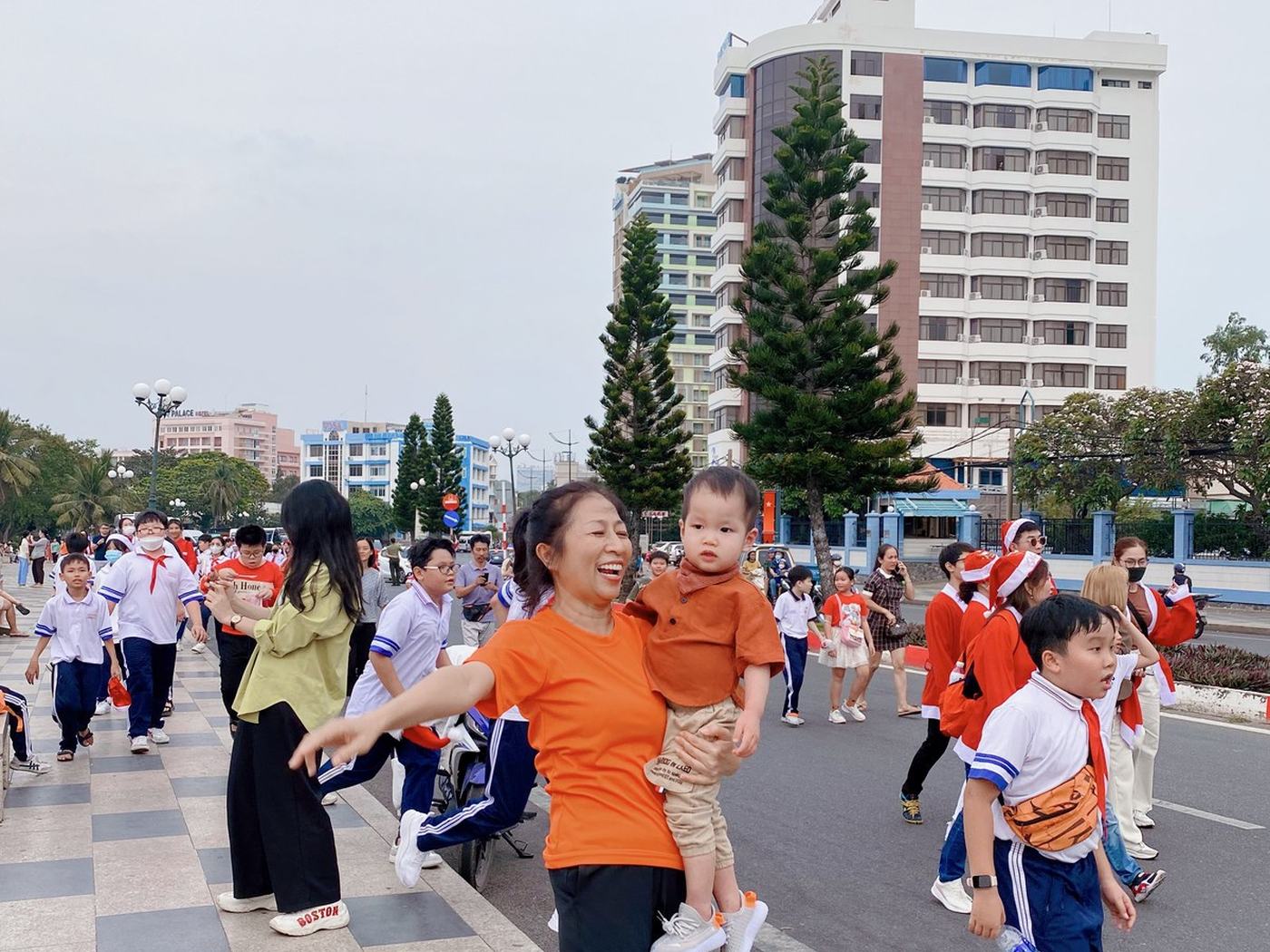 Nền loạn — cùng nhóm ấy đứng giữa dòng người, sau lưng là học sinh và xe máy